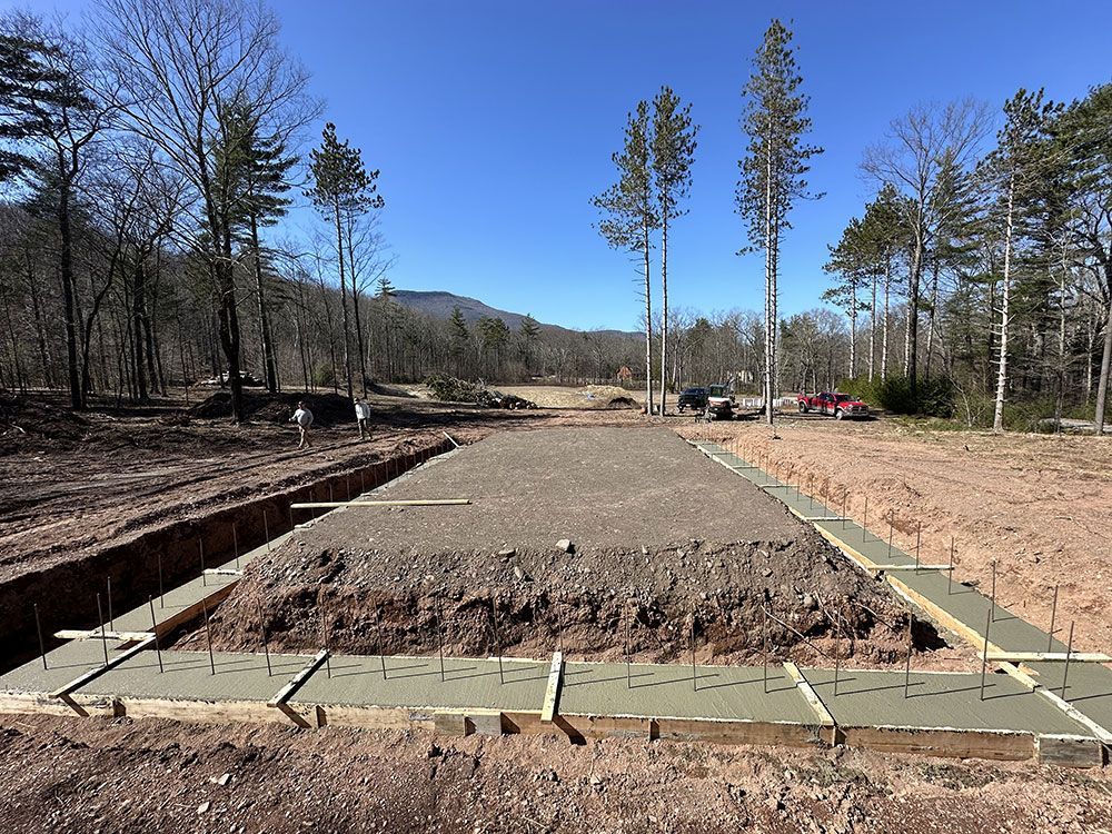 A construction site with a lot of dirt and trees in the background.