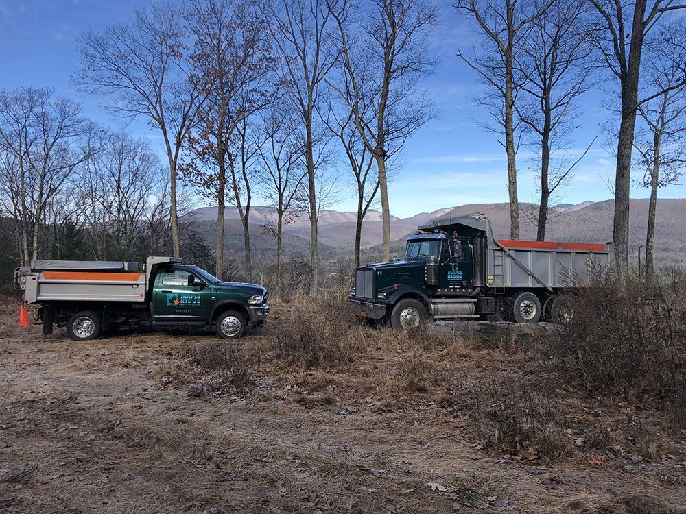 Two dump trucks are parked next to each other in a field.
