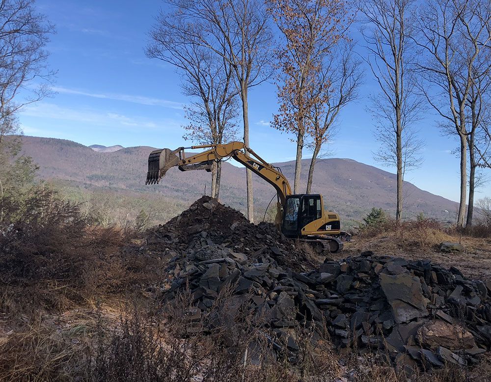 A bulldozer is moving a pile of rocks in a field.