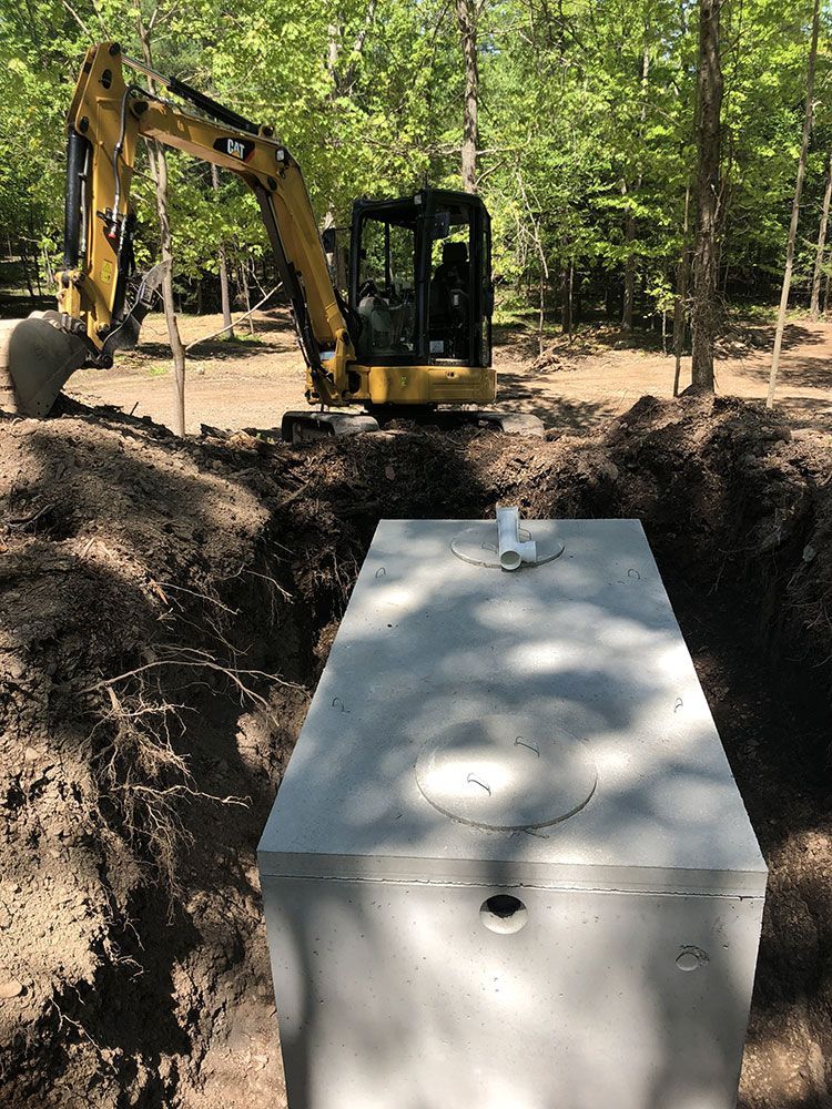 A large concrete septic tank is being installed in a dirt field.