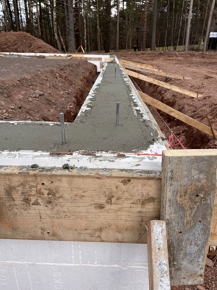 A concrete foundation is being built in the middle of a dirt field.