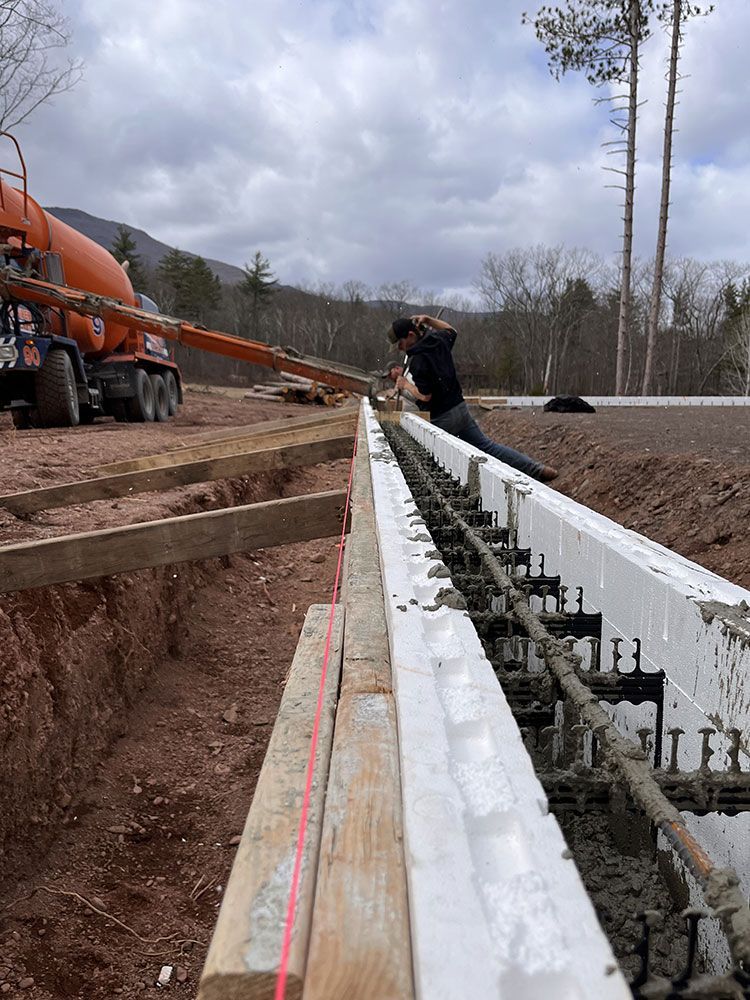 A man is pouring concrete into a trench on a construction site.