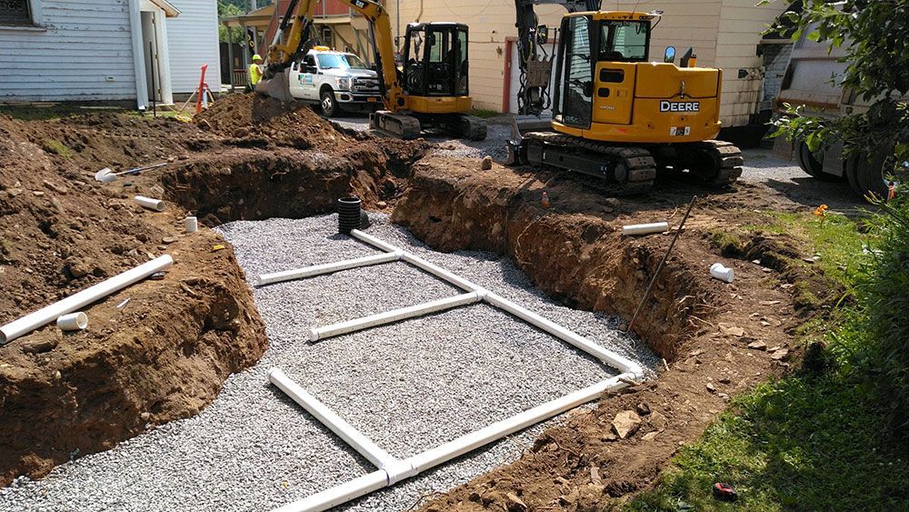 A yellow excavator is digging a hole in the dirt in front of a house.