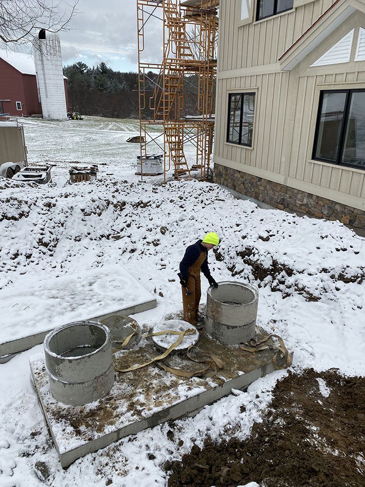 A man is standing in the snow next to a house.