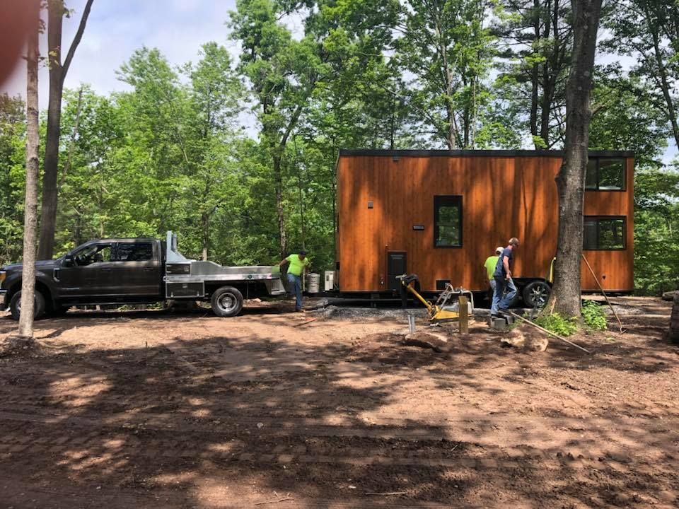 A truck is towing a tiny house in the woods.