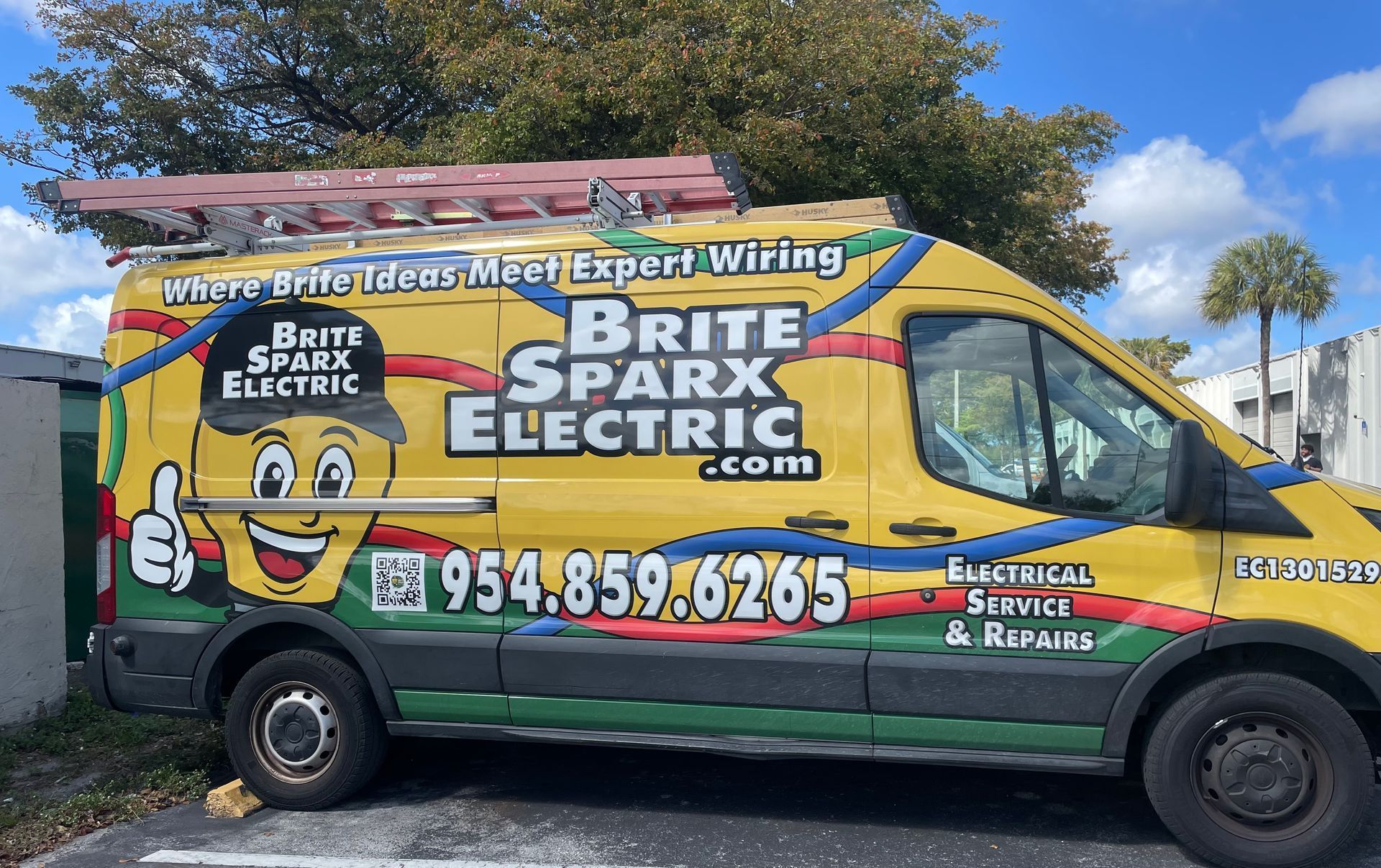 Yellow work van with Brite Sparx Electric branding, a lightbulb mascot, and contact information, parked outdoors.