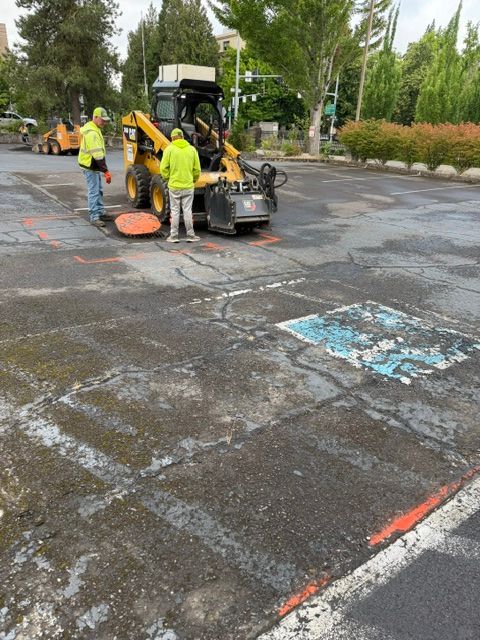 Road crew in yellow vests repairing cracked asphalt with a machine