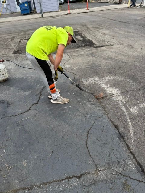 A worker in a neon shirt fixing a cracked asphalt road