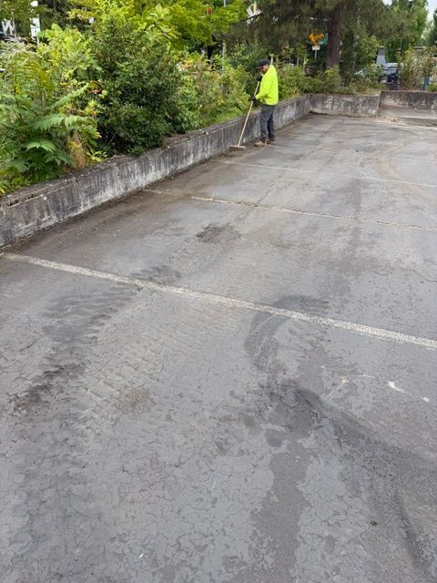 Person in a neon jacket standing beside a wet concrete path with greenery along the edge