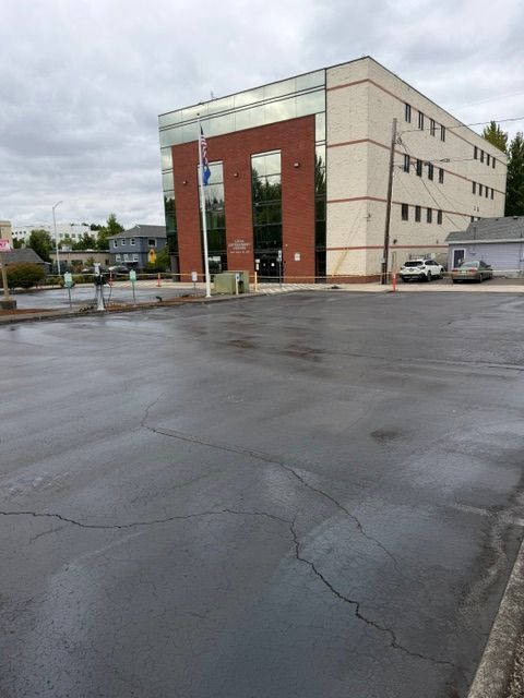 Large parking lot beside a beige-and-red multi-story building on a cloudy day