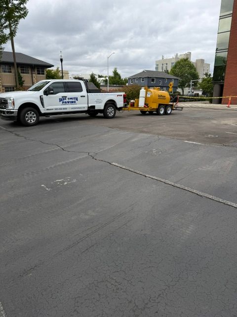 White pickup truck towing a yellow trailer in a parking lot near a building