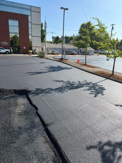 Empty parking lot beside a red brick building with a newly paved black surface