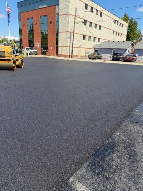 Freshly paved road beside a tan building
