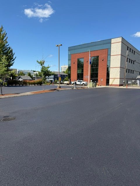Modern building beside an empty paved lot under a blue sky