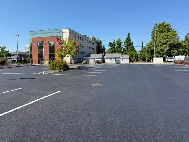 Empty parking lot beside a beige and red building under a clear blue sky
