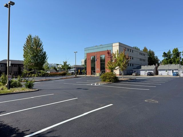 Empty parking lot outside a modern building with brick columns and blue sky