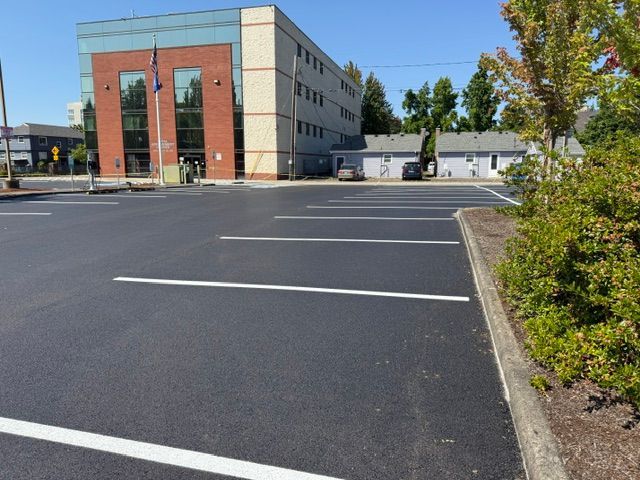 Empty parking lot beside a modern office building with brick and gray exterior