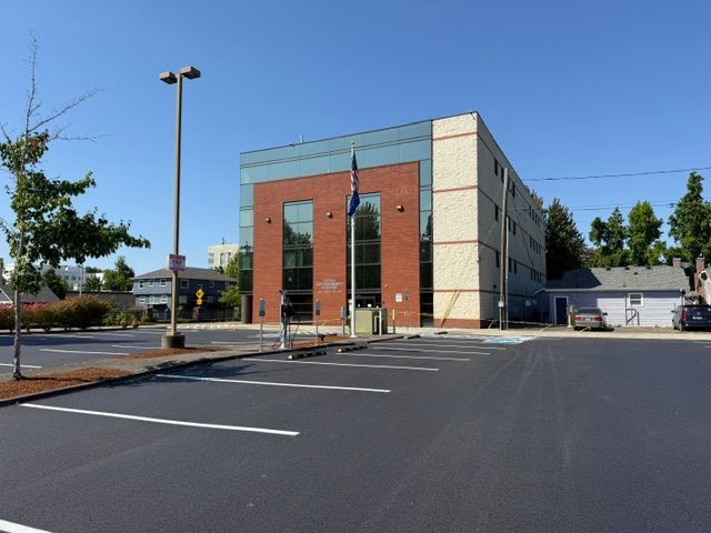 Empty parking lot outside a modern brick and concrete office building on a sunny day
