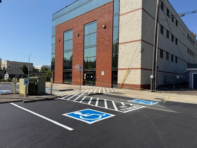 Accessible parking spaces outside a brick building with glass entrance and white-striped ramp.