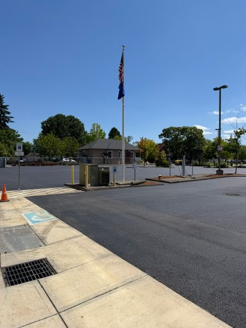 Small guard booth and flagpole in a mostly empty parking lot on a sunny day