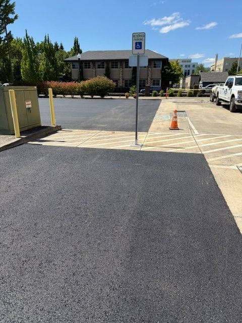 Parking lot entrance with accessible curb ramp, yellow tactile strip, and orange cone outside a building