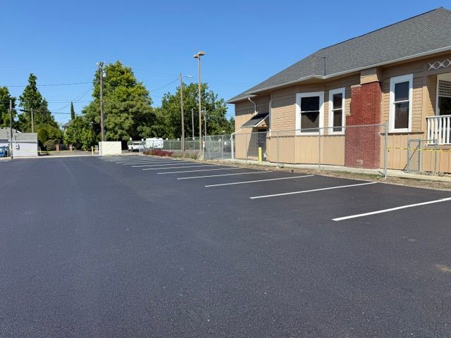 Empty parking lot beside a brick building under a clear blue sky