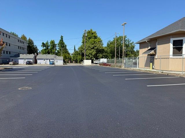 Empty parking lot beside beige buildings under a clear blue sky