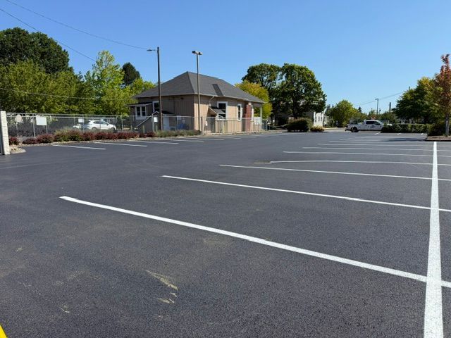 Empty parking lot beside a small building and trees on a sunny day