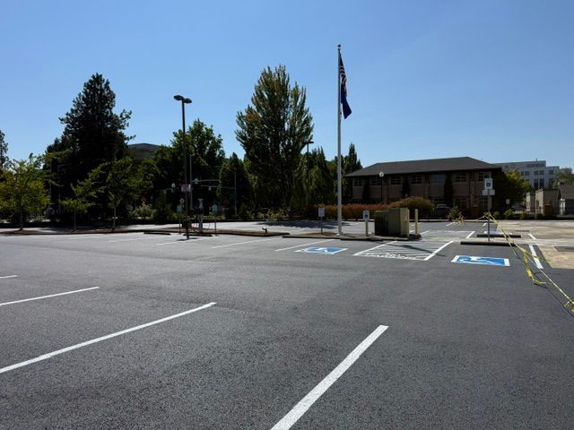 Empty parking lot with accessible spaces, trees, and a building under a clear sky