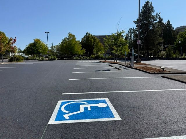Accessible parking space marked in a mostly empty parking lot on a sunny day