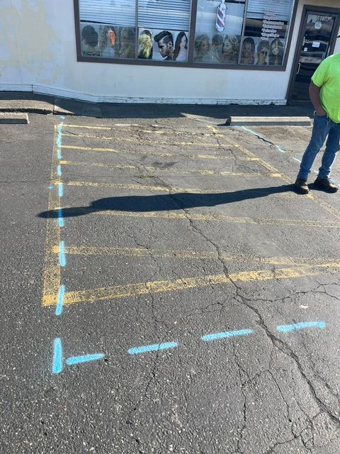 Parking lot pavement marked with blue tape lines near a building entrance, with a person standing at right.