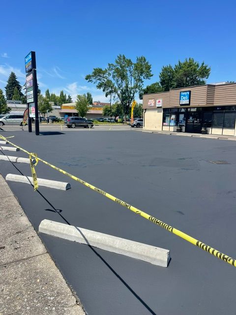 Caution tape blocks a mostly empty parking lot beside a strip mall on a sunny day.