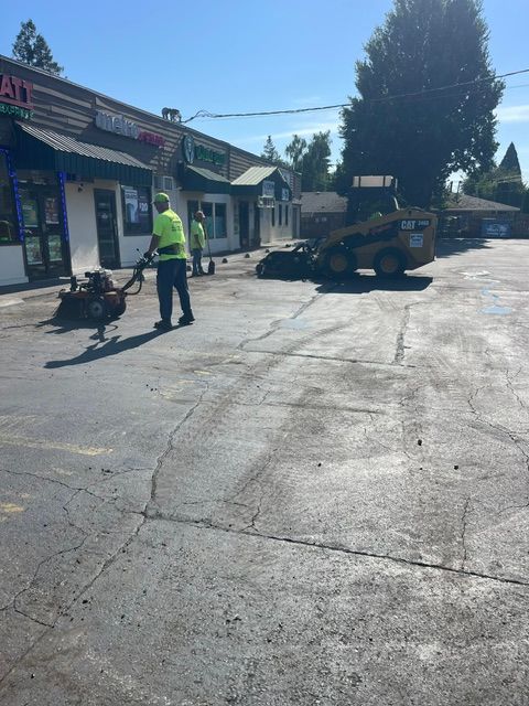 Worker in neon vest beside a skid steer on a sunny street near storefronts
