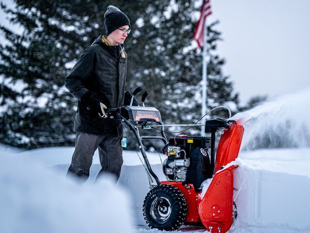 a man is pushing a snow blower in the snow