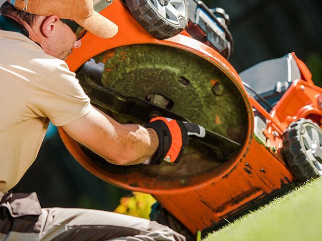 a man is repairing a lawn mower on a lush green lawn