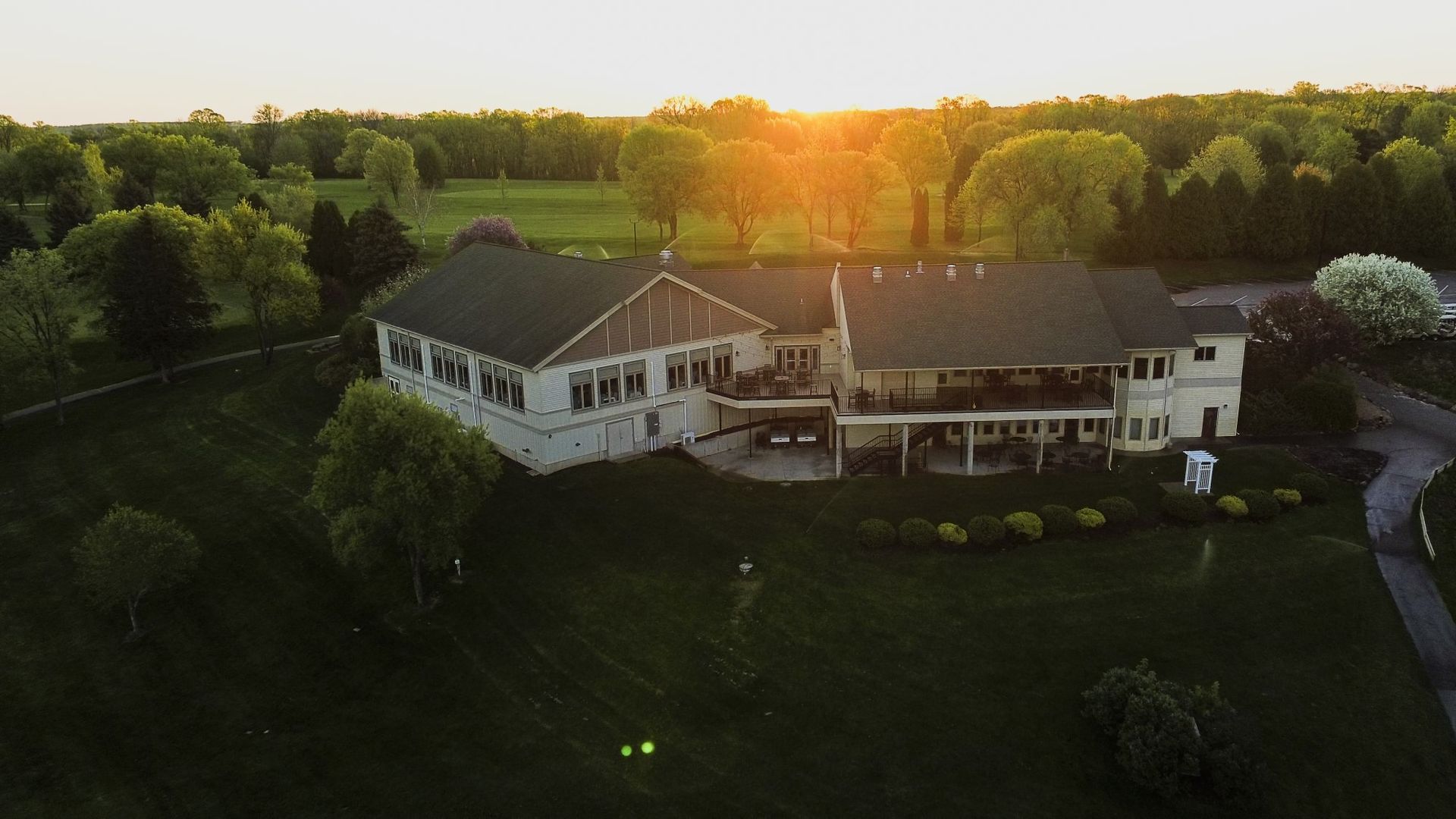 An aerial view of a large house in the middle of a lush green field.