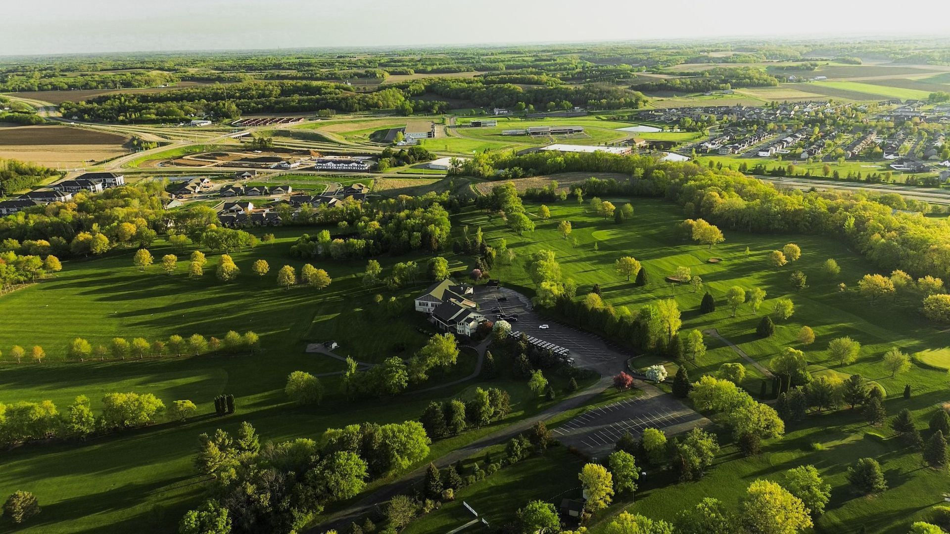 An aerial view of a golf course surrounded by trees and fields.