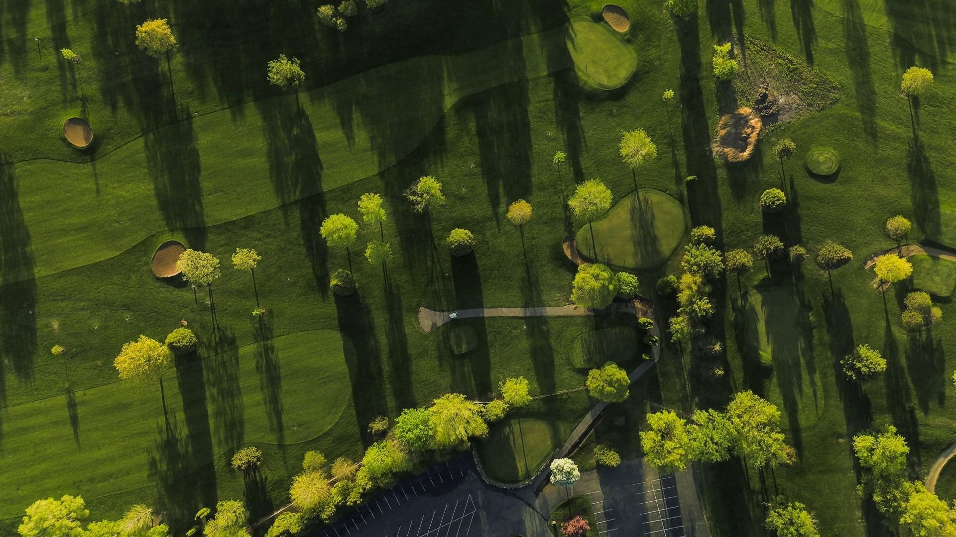 An aerial view of a golf course surrounded by trees and grass.