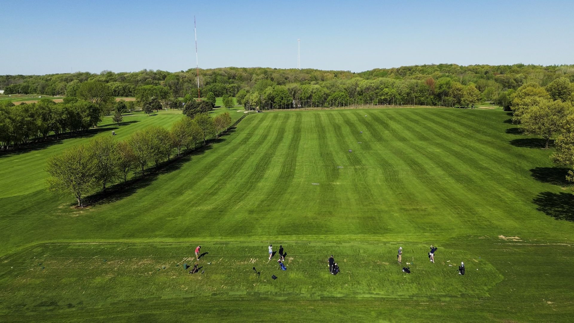 An aerial view of a lush green field with trees in the background.
