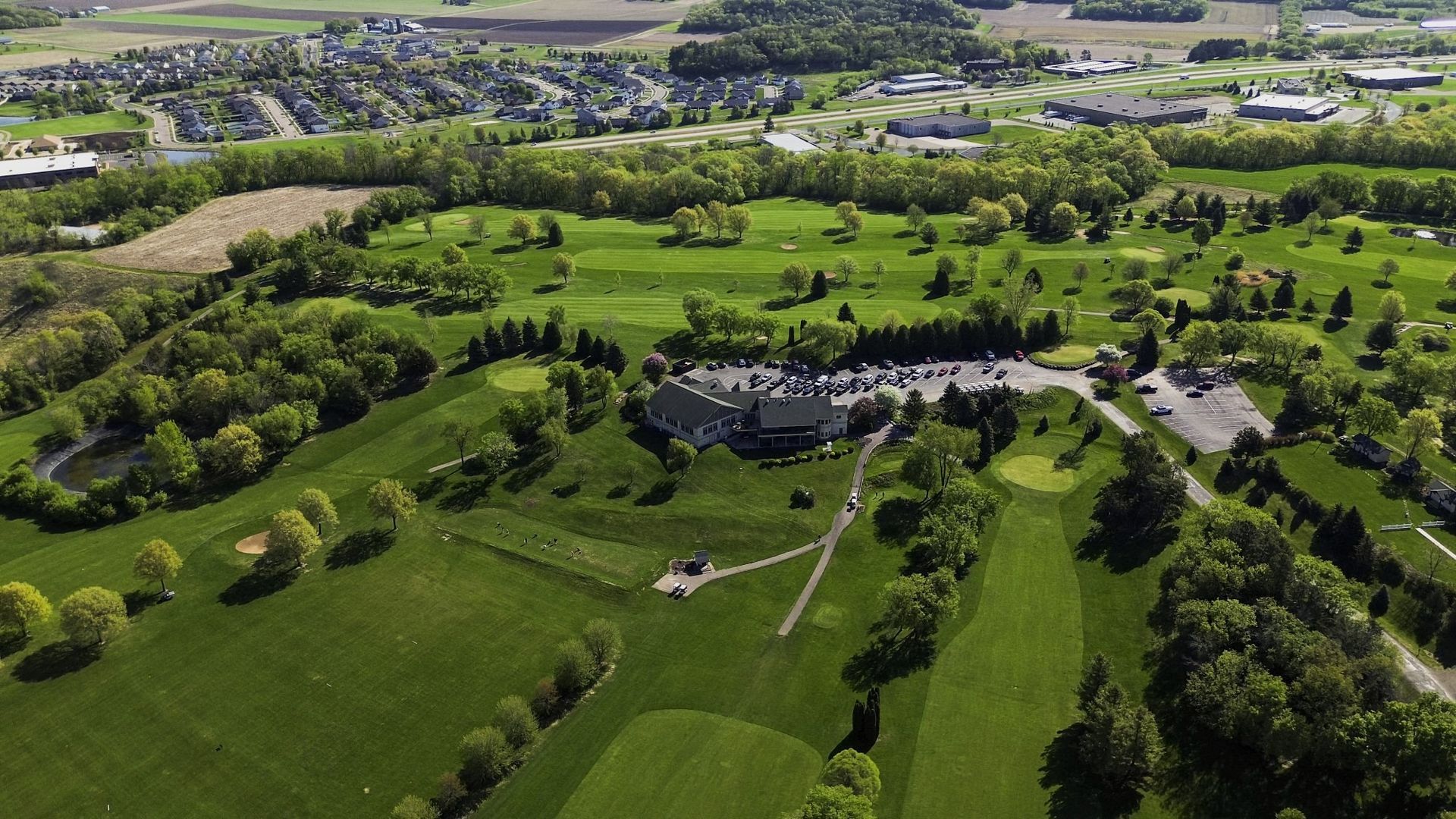 An aerial view of a golf course surrounded by trees and houses.