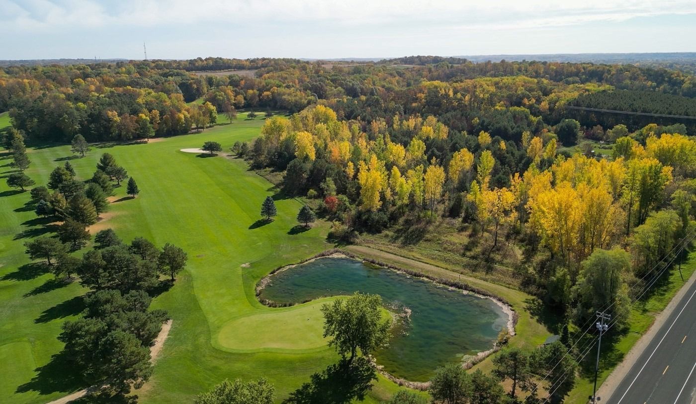 An aerial view of a golf course surrounded by trees and a lake.