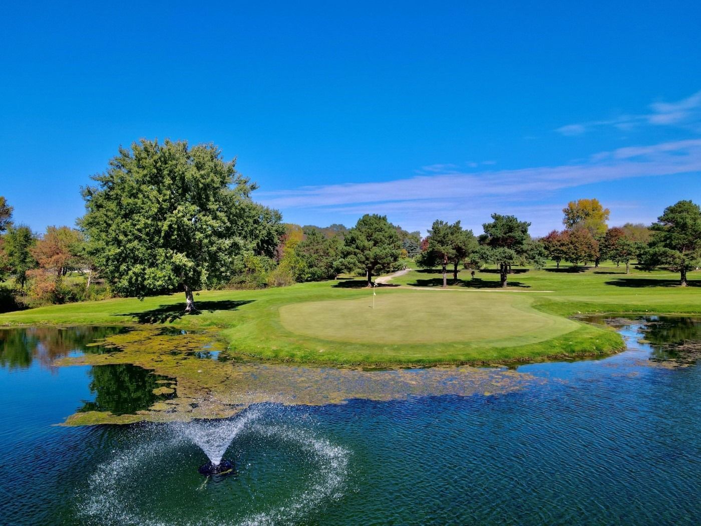 A golf course with a fountain in the middle of the water.