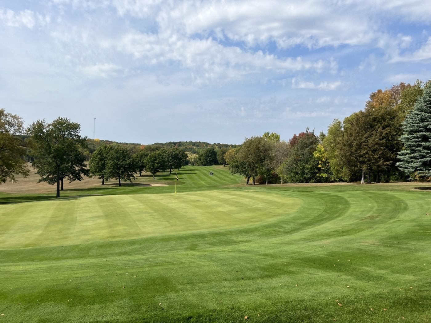 A golf course with a lot of green grass and trees in the background.