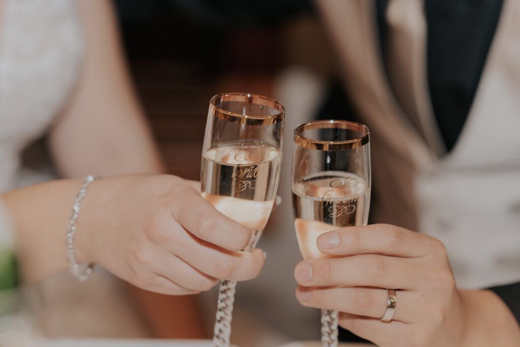 Two people toasting with champagne flutes; gold-rimmed glasses, celebratory.