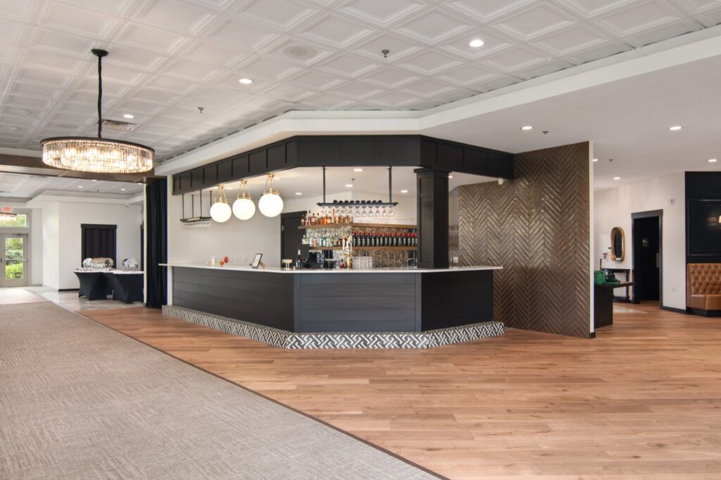 Modern event space with a dark bar, patterned ceiling, and wood floor.
