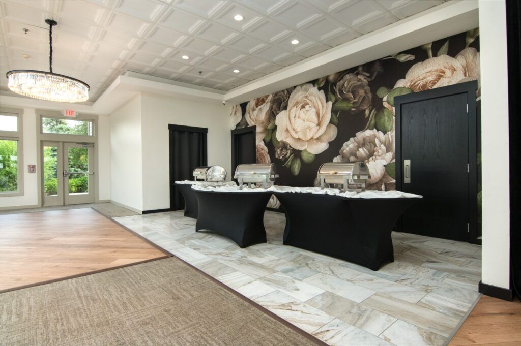 Banquet hall with buffet tables against a floral mural and wood dance floor.