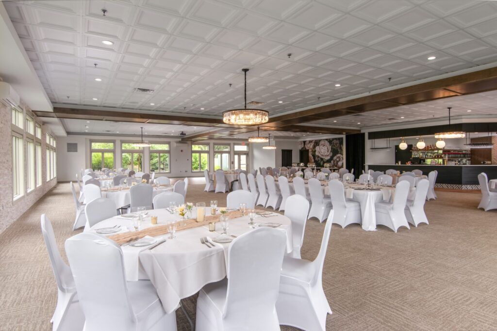 Banquet hall with round tables set for a wedding reception, with white linens and chairs.