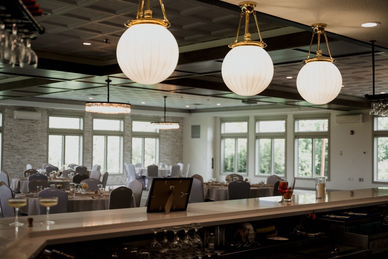 Elegant event space with a bar, round globe lights, and tables set for guests.