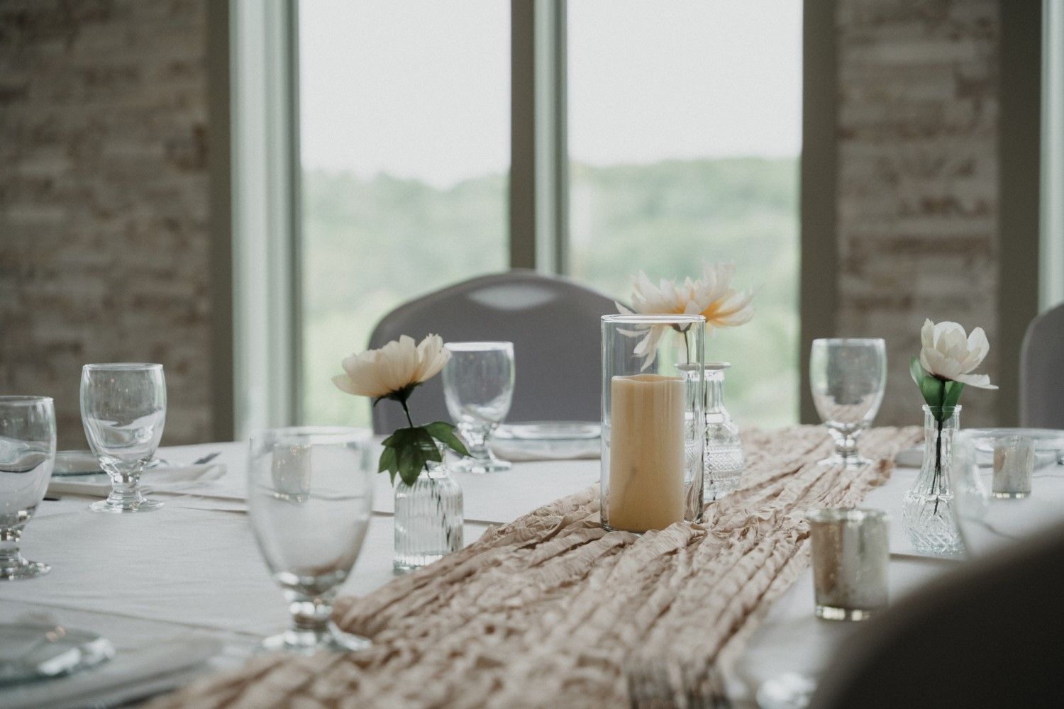 Wedding reception table with flowers, candles, and glasses set for guests.