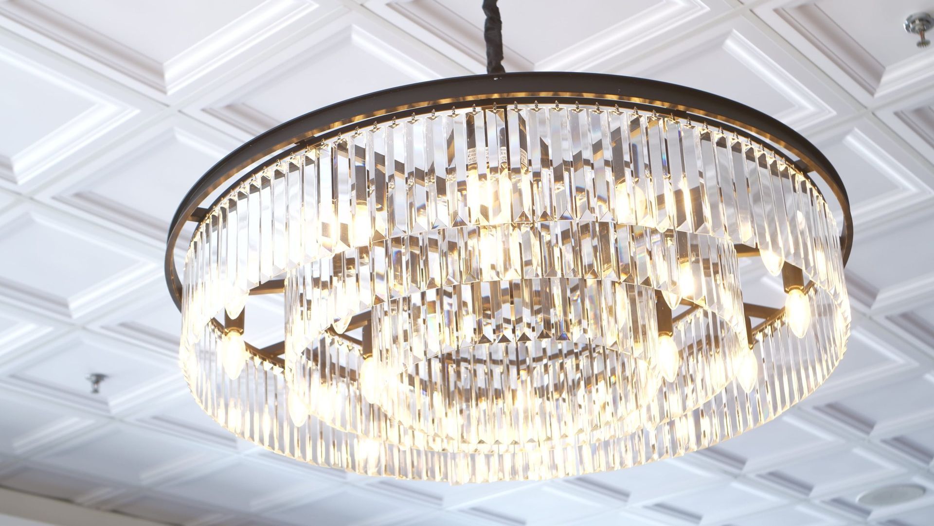 Crystal chandelier hanging from a white, textured ceiling.